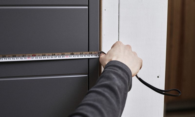 Mies mittaa mittanauhalla oven leveyttä.